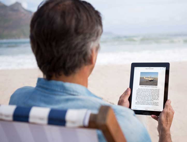 Reflowable ebook being read on a Kindle ereader at a sandy beach.